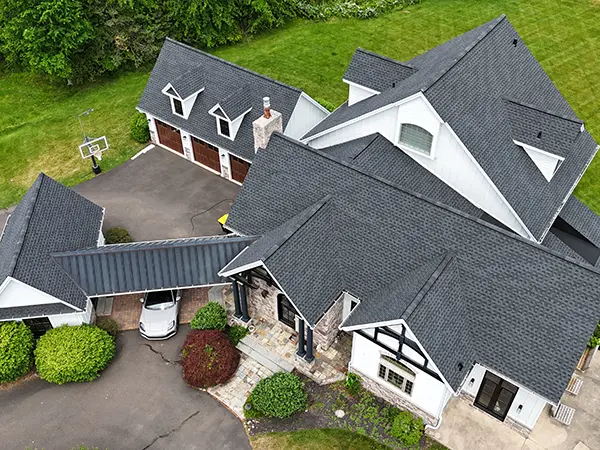 High-end home with new dark gray GAF shingles and metal roof accent installed